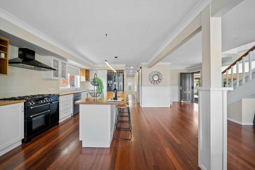 a kitchen with white cabinets and a wooden floor at Karinya Jervis Bay - 4BR home & optional studio in Vincentia