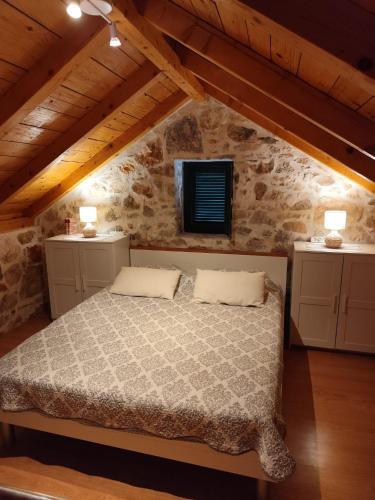 a bedroom with a bed in a stone wall at Krka Waterfalls Stonehouse Roko in Lozovac
