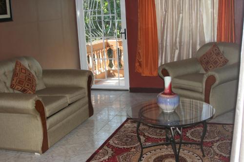 a living room with two couches and a glass table at Cozy Apartment in Kingston
