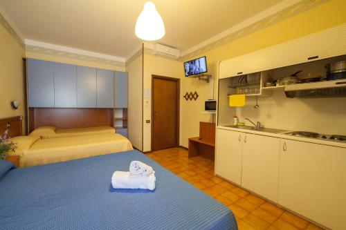 a bedroom with two beds and a sink and a kitchen at Hotel Ricordo Du Parc in Tabiano