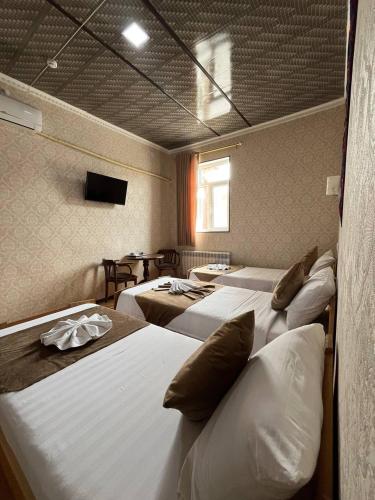 a room with four beds and a tv on the wall at Polvon Ota Hotel in Khiva