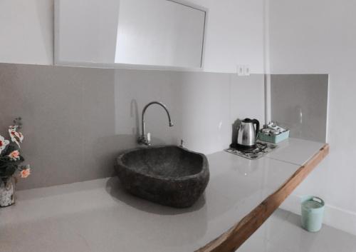 a bathroom with a stone sink on a counter at Anorawi Surf accommodation in Maluk