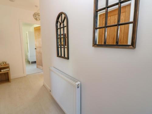 a hallway with a mirror and a radiator on a wall at Blacksmiths Cottage in Alnwick