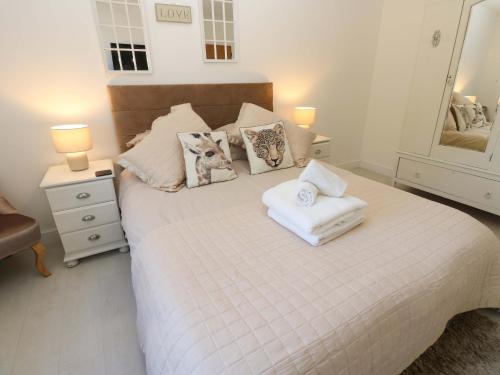 a bedroom with a white bed with towels on it at Blacksmiths Cottage in Alnwick
