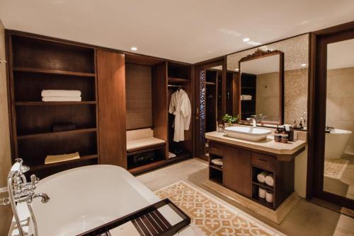 a bathroom with a tub and a sink and a mirror at Ramayana Suites and Resort in Kuta