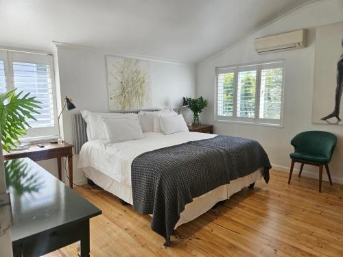 a bedroom with a large bed and two windows at Cherry Tree House, Newlands in Cape Town