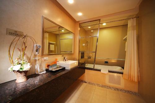 a bathroom with a sink and a mirror and a tub at R7 Hotel in Kaohsiung