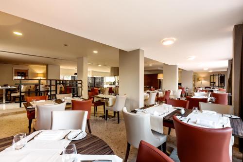 a dining room with white tables and chairs at Vilamoura Garden Hotel in Vilamoura