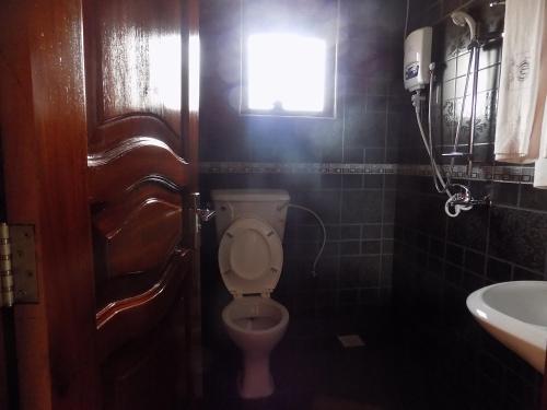a bathroom with a toilet and a window and a sink at Olina Hotel and Apartments Kampala in Kampala