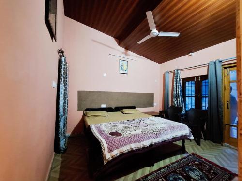 a bedroom with a bed and a ceiling fan at TATHASTU RETREAT BiR -TRB in Bīr