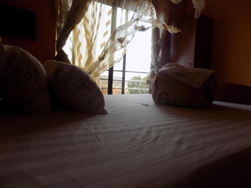 a bed with two pillows in a room with a window at Olina Hotel and Apartments Kampala in Kampala