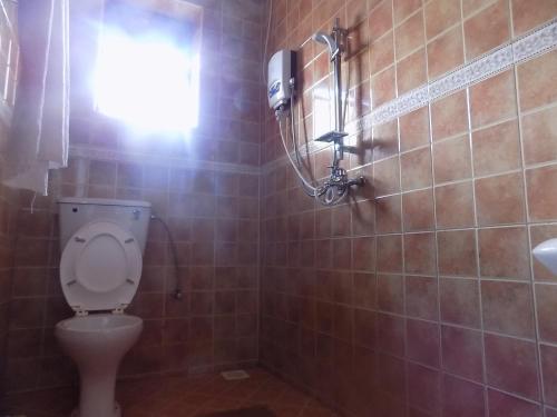 a bathroom with a toilet and a window and a shower at Olina Hotel and Apartments Kampala in Kampala