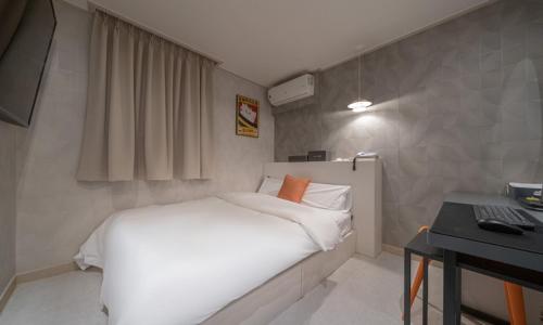 a small bedroom with a white bed and a desk at Uiwang Nine Hotel in Uiwang