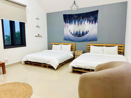two beds in a room with a chair and a couch at LaLa Villa Đà Lạt in Da Lat