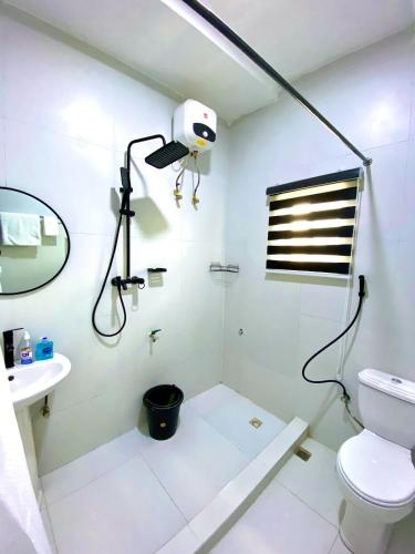 a white bathroom with a shower and a toilet at Aulein Apartments in Abuja