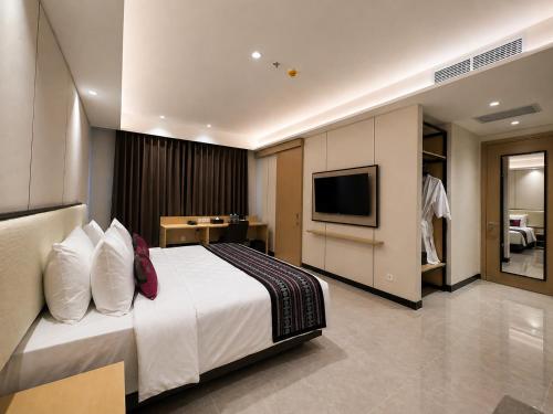 a hotel room with a bed and a television at Prime Plaza Hotel Mataram in Mataram