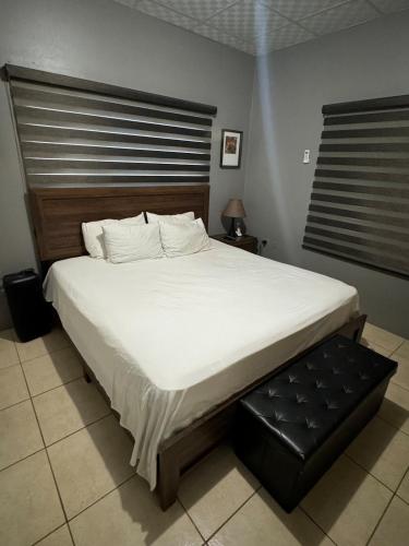 a bedroom with a large bed with white sheets and a bench at Casa No6 Ascot in Carapo