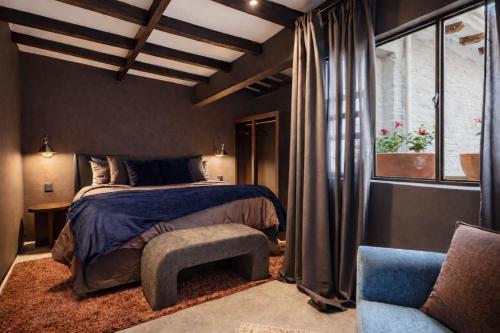 a bedroom with a bed and a chair and a window at Casa UMA in San Miguel de Allende