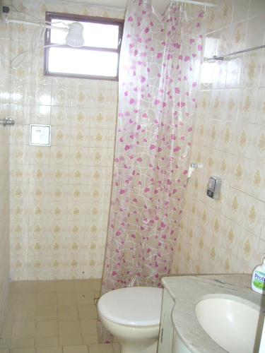 a bathroom with a toilet and a pink shower curtain at Pousada Ana Poipa in Goiânia
