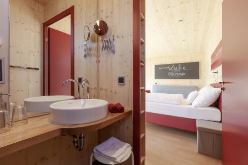 a bathroom with a sink and a bed in a room at mein kleinHOTEL in Herbstein