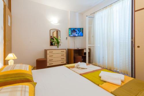 a bedroom with two beds and a dresser and a television at Apartments Slavica in Pomena