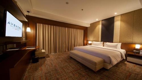 a hotel room with a bed and a flat screen tv at Avenzel Hotel & Convention Cibubur in Cibubur
