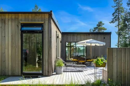 a wooden house with a deck and an umbrella at Architect Villa By Cliff Bathing In High Coast in Härnösand