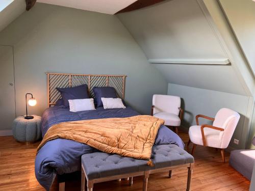 a bedroom with a bed with a blue comforter and two chairs at 32-La Place To Be in Senlis