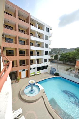 a person standing in front of a building with a swimming pool at Hotel La Aldea in Atacames