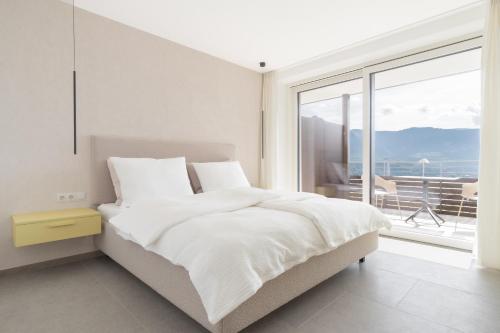 a white bedroom with a bed and a large window at Ferienwohnungen Steinegg in Lagundo