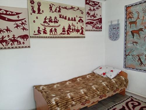 a room with a bed and paintings on the wall at Guest House Aruuke in Naryn