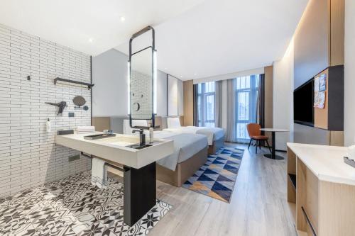 a hotel room with a bed and a sink and a mirror at Wanda Moments Nanchang in Xinjian