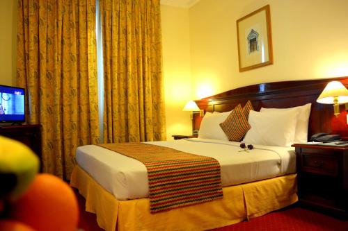 a hotel room with a bed and a television at York International Hotel in Dubai