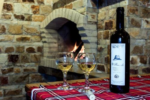 two glasses of white wine on a table with a fireplace at Divna Guest House in Dospat
