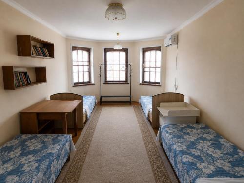 a room with two beds and a table and windows at Uyut house Osh in Osh