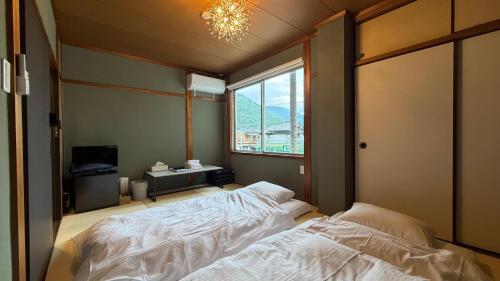 a bedroom with a bed and a window at hostel大黒屋 in Miyoshi