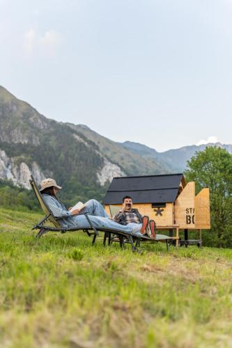 two people laying on lawn chairs in a field at StarsBOX - La Vrata Gialla in Montemaggiore
