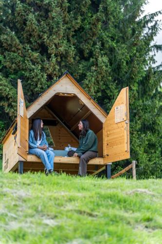 a man and woman sitting in a wooden dog house at StarsBOX - La Vrata Gialla in Montemaggiore