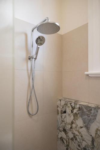 a shower with a shower head in a bathroom at Belle Escapes Henley's Coastal Charm in Henley Beach South