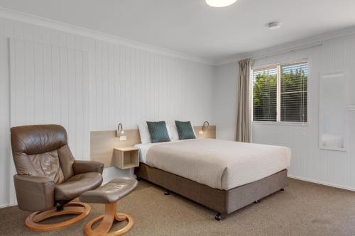 a bedroom with a bed and a chair at Raintree Motel Biloela in Biloela