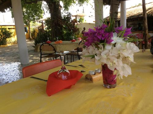 a yellow table with a vase of flowers on it at Campement Le Cormoran in Ndangane
