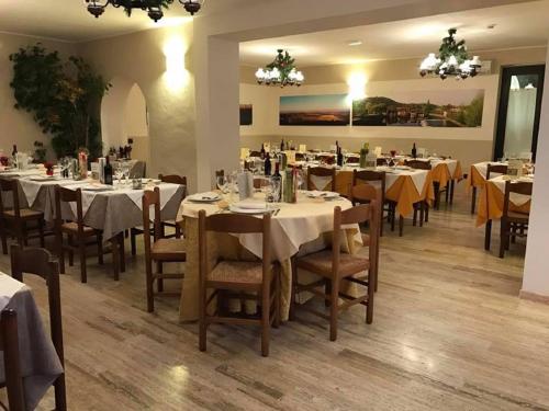 una sala da pranzo con tavoli e sedie bianchi di Hotel Ristorante La Grotta a Castiglione delle Stiviere