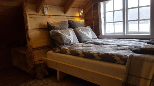 ein Bett in einer Blockhütte mit Fenster in der Unterkunft Tiny house with Fjordview! in Lauvstad