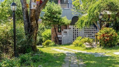 a garden with a stone path and a fence at Yangyang Little Forest Pension in Yangyang