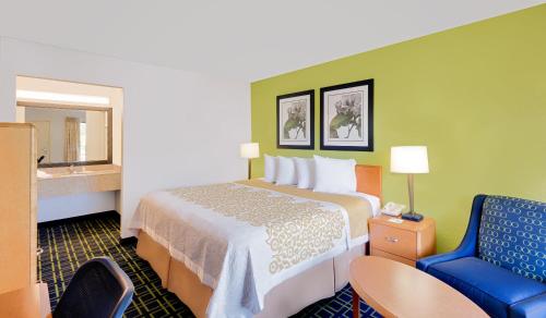 um quarto de hotel com uma cama e uma cadeira azul em Days Inn by Wyndham Easton em Easton