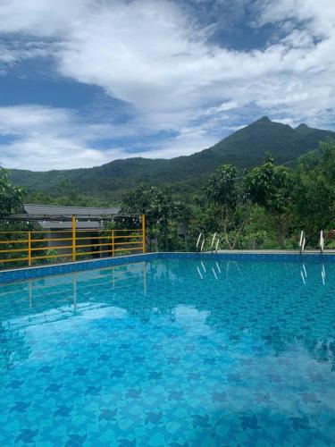 a large blue swimming pool with mountains in the background at Educational Eco Ba Vi in Thủ Pháp