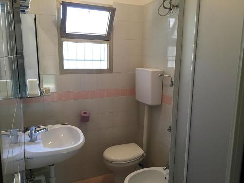 a bathroom with a sink and a toilet and a window at Villaggio Arco in Eraclea Mare