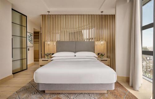 a bedroom with a large white bed and a large window at Hyatt Regency London Olympia in London