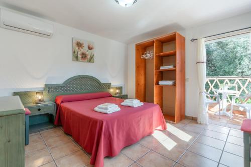 a bedroom with a red bed with a desk and a window at Cortijo Corral del Gallo in Órgiva