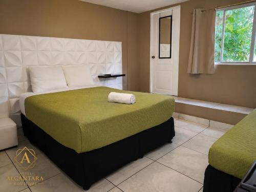 a bedroom with a large bed with a green blanket at Hotel Alcántara Boutique in San Salvador
